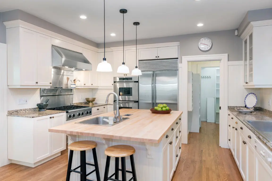 Amazing luxury kitchen interior in white with wooden floor and kitchen island.