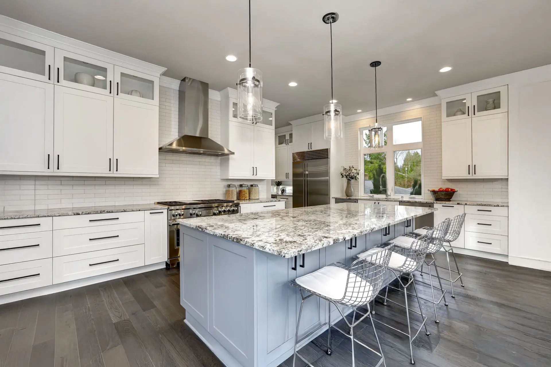 Beautiful kitchen in luxury home interior with island and stainless steel chairs.