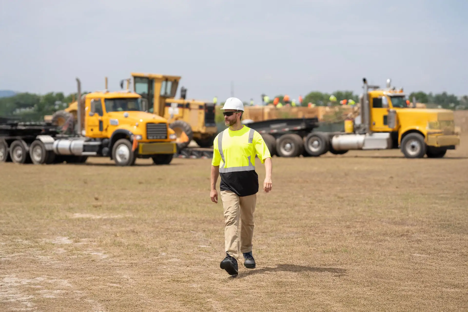 Construction worker walking in an open patch of dirt in an open construction site.