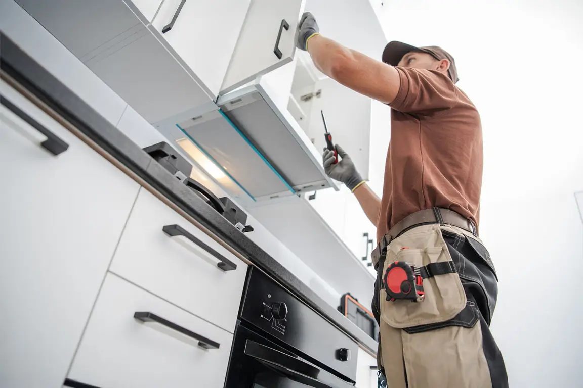 Residential Cabinetmaker Worker Finishing New Kitchen Installation.