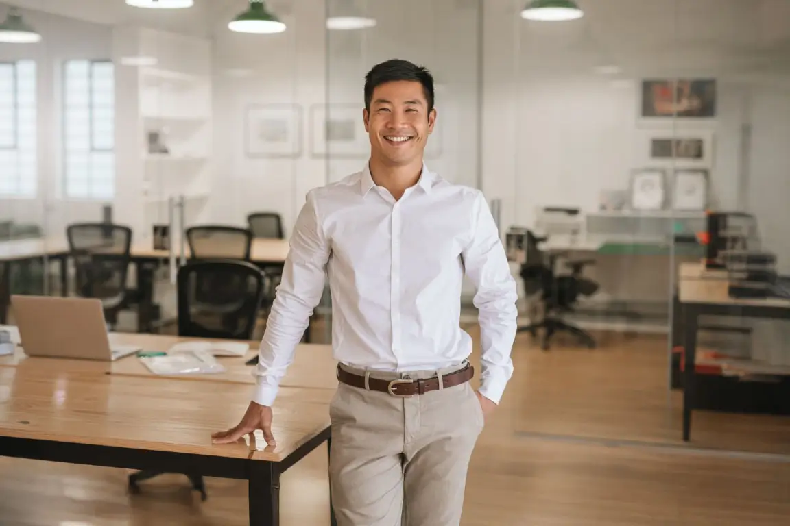 Young Asian businessman standing in an office smiling confidently.