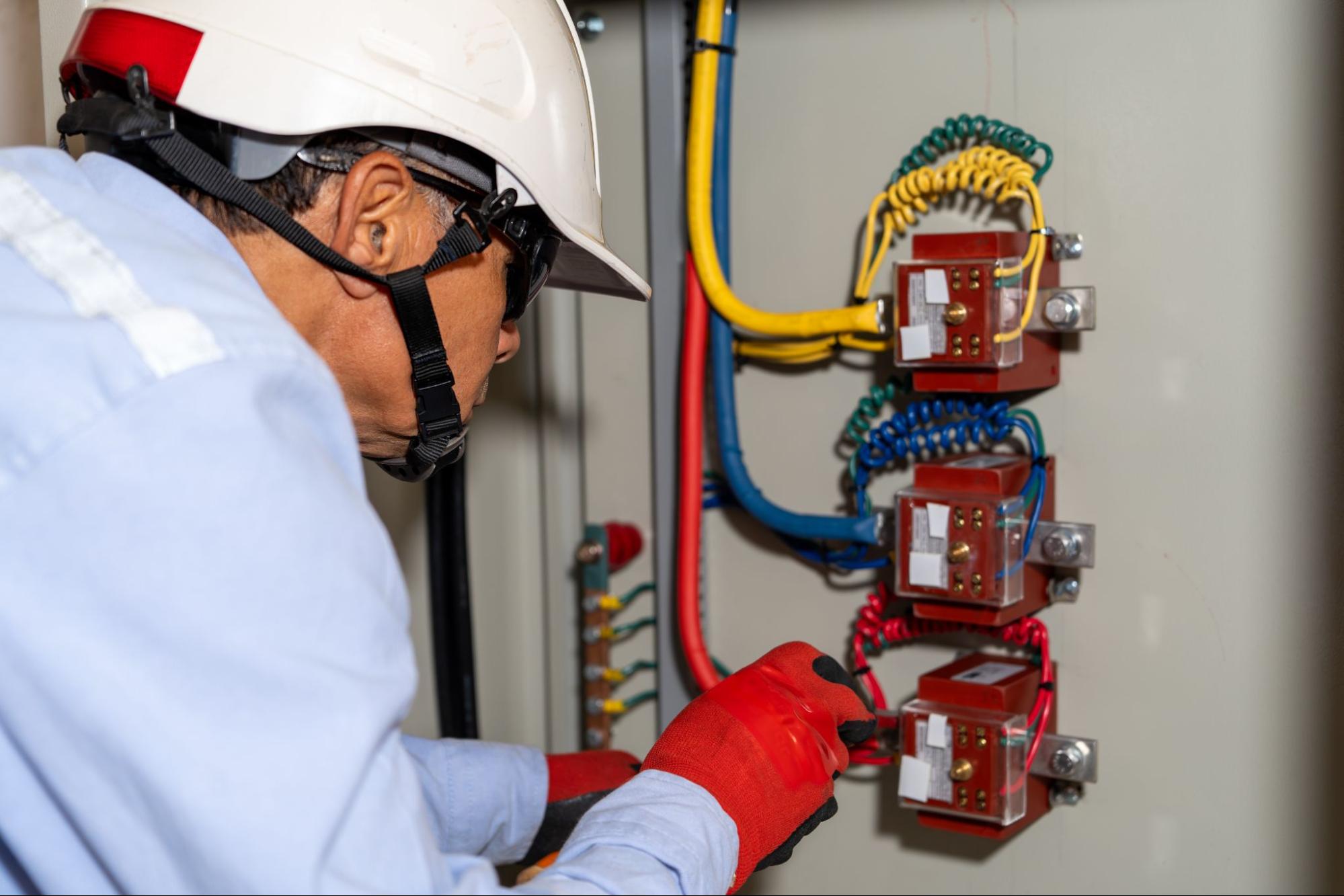 An engineer servicing high-voltage components in an industrial panel