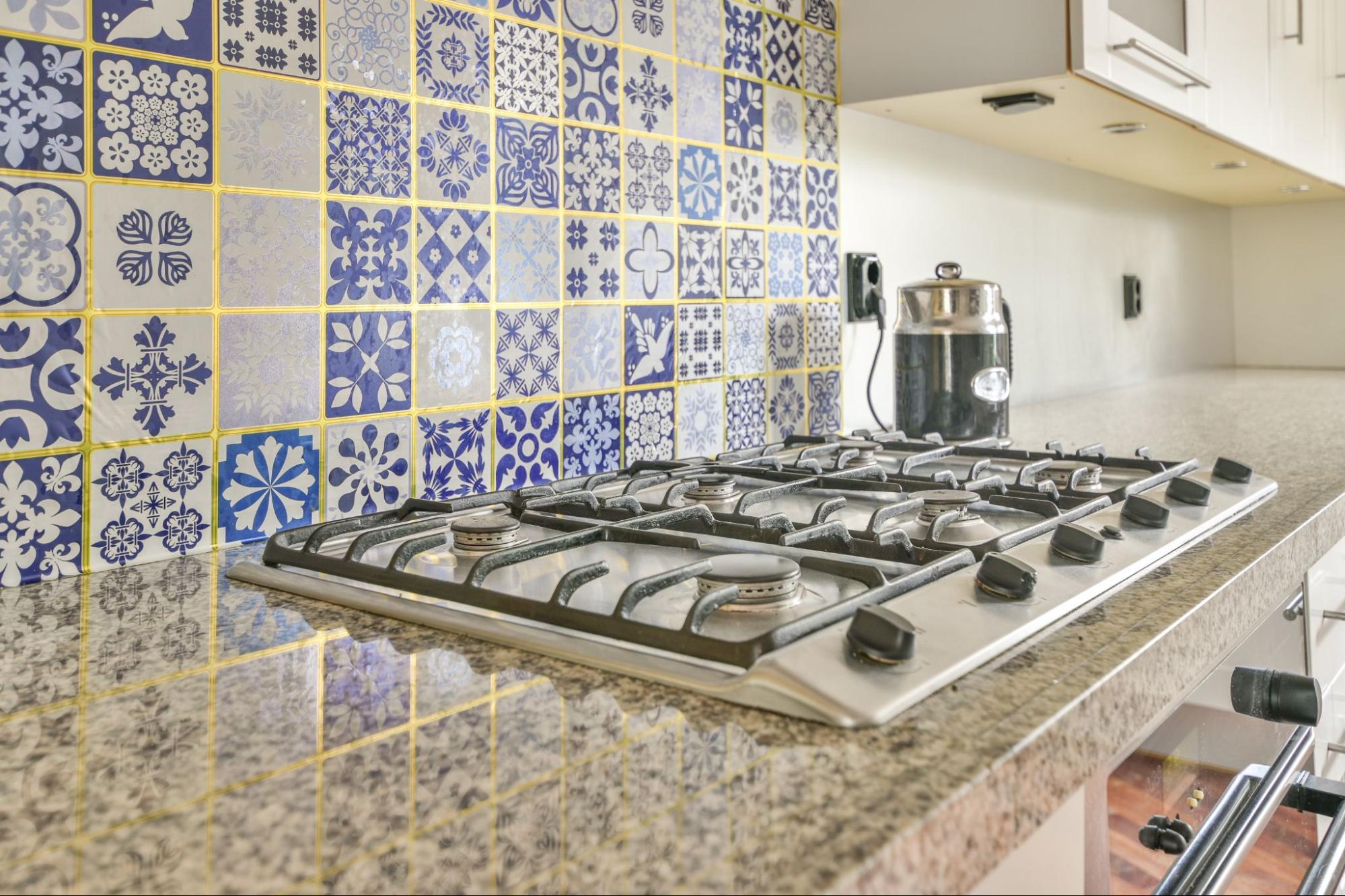 A gas stove with blue and gold kitchen backsplash tile.