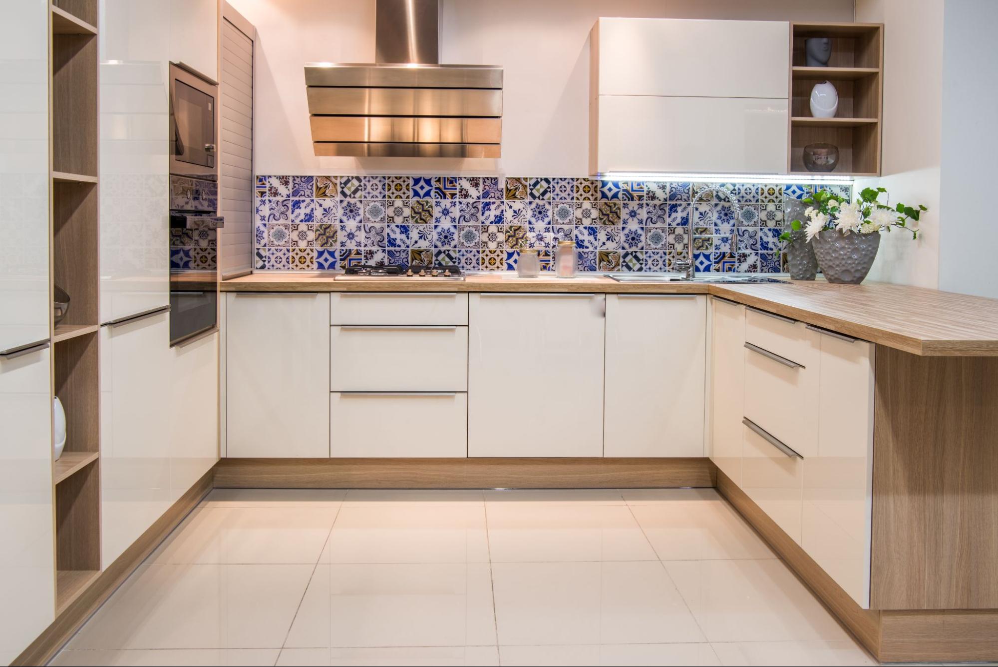 A kitchen with a blue and white backsplash offset with neutral tone floor tiles and counters.
