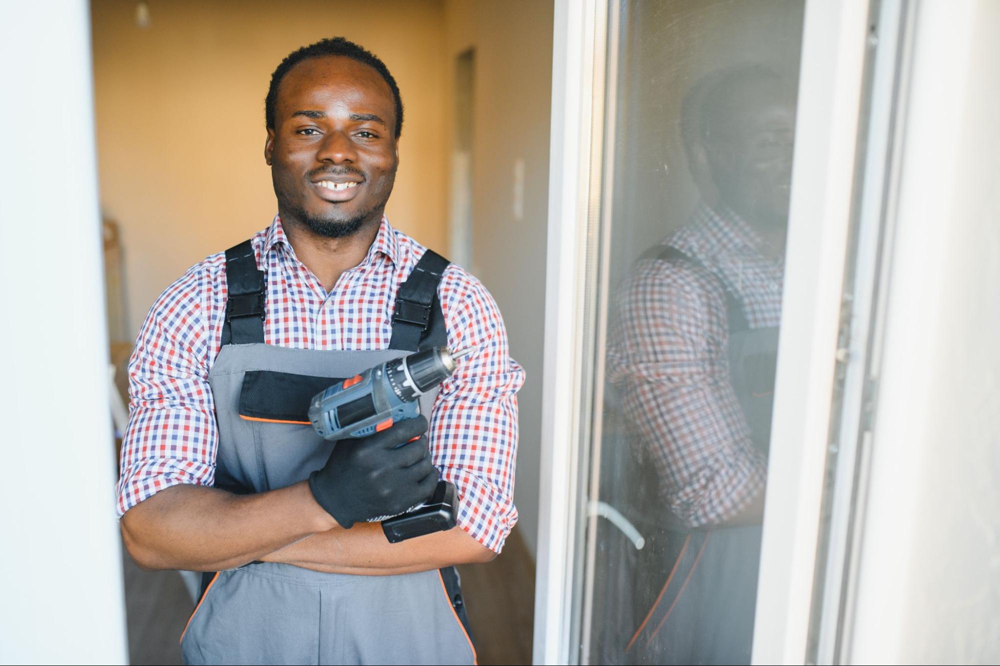 A local handyman smiles for the camera after repairing a door with his drill.